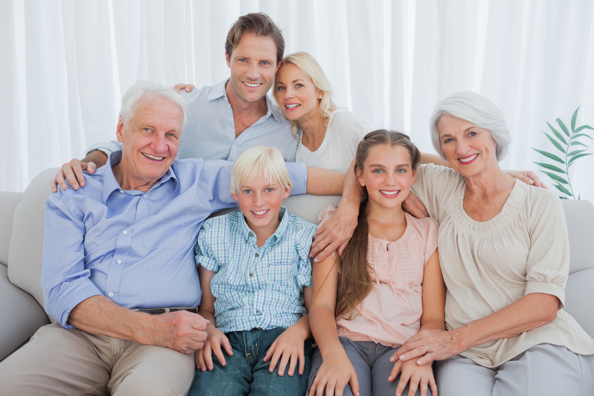 Zdjęcie całej rodziny, przedstawiające trzy pokolenia, dziadków, dzieci i wnuki. Wszyscy się obejmują i są szczęśliwi.
